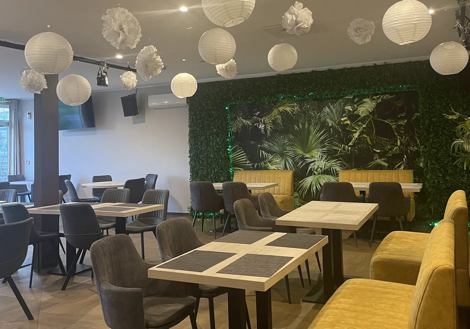 Salle du Kfé-Kko : lanternes, mur végétal et banquettes jaunes